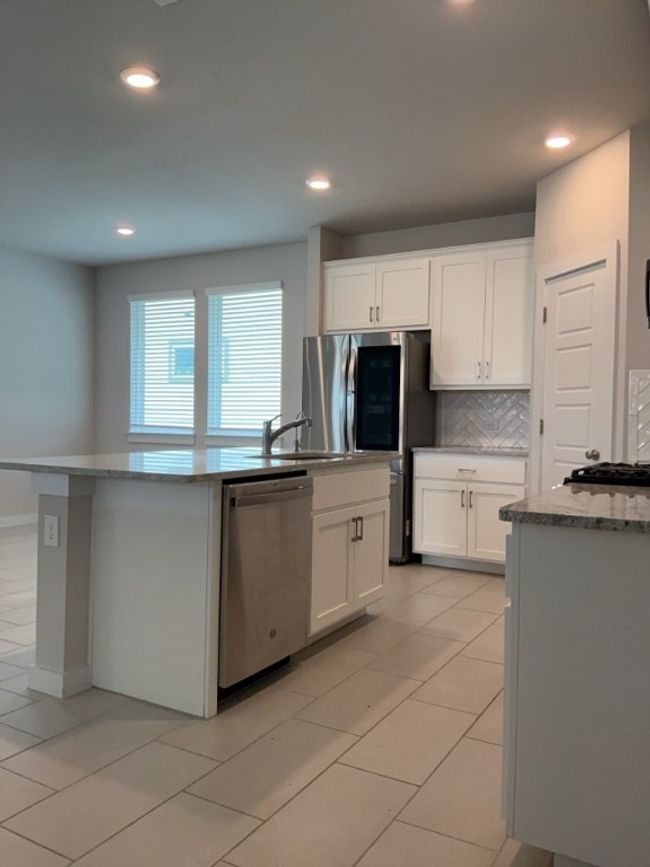 Kitchen featuring stainless steel appliances, white cabinetry, tasteful backsplash, recessed lighting, and an island with sink | Image 7