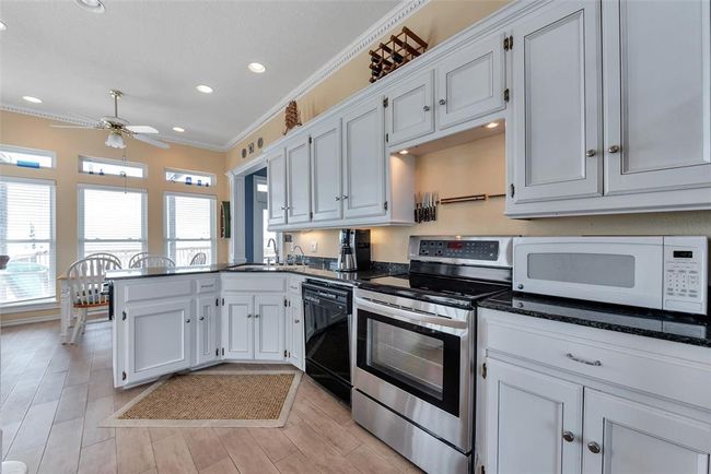 The kitchen layout keeps cooking essentials close at hand with upper and lower cabinet storage, built-in knife rack, and seamless flow to the dining area. Designed for both convenience and connection. | Image 15