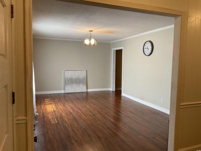 Unfurnished room featuring dark hardwood / wood-style floors, a textured ceiling, a chandelier, and ornamental molding | Image 3