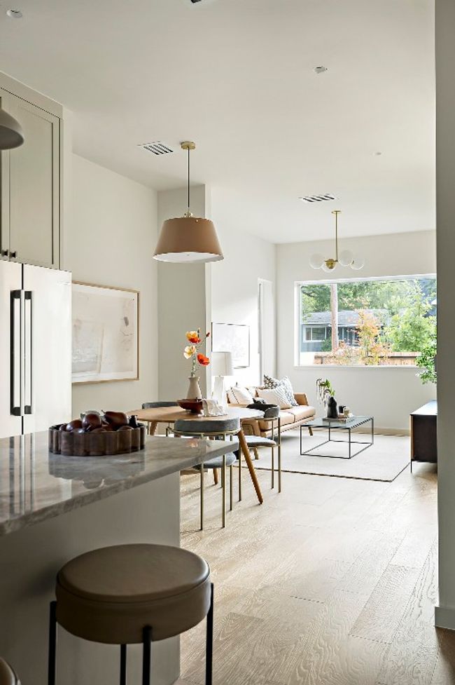 Kitchen featuring light wood-style floors, decorative light fixtures, freestanding refrigerator, dark stone counters, and open floor plan | Image 11