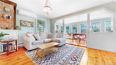 Living room featuring light hardwood / wood-style floors, a notable chandelier, baseboard heating, and a wall mounted air conditioner | Image 2