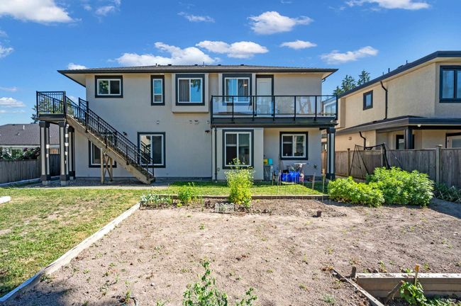 Rear view of house with a fenced backyard, stairs, a garden, and stucco siding | Image 39