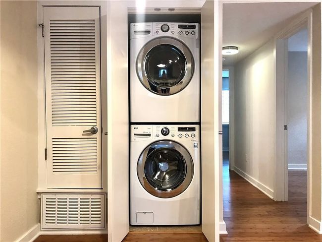 Washroom featuring stacked washer / drying machine and wood finished floors | Image 7