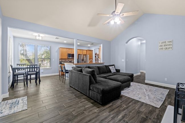 Living area with ceiling fan, dark wood-type flooring, arched walkways, vaulted ceiling, and baseboards | Image 8
