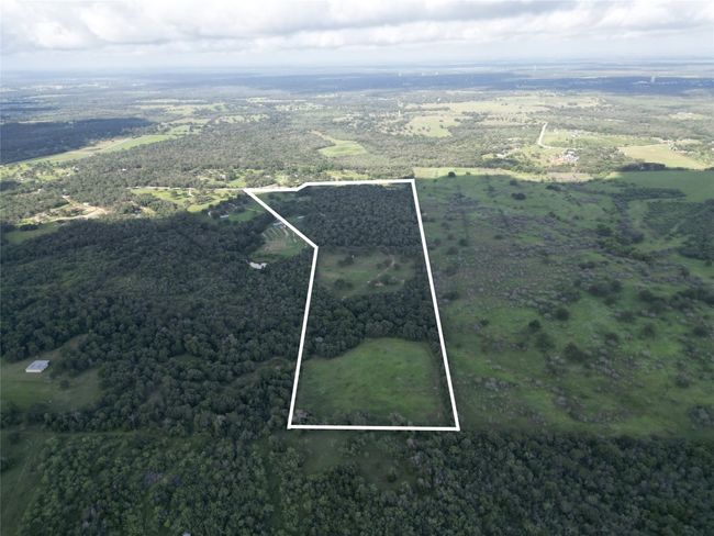 Aerial overview of property's location featuring property parcel outlined and a heavily wooded area | Image 24