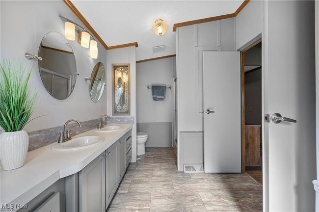 Bathroom featuring double vanity, ornamental molding, and a wainscoted wall | Image 16
