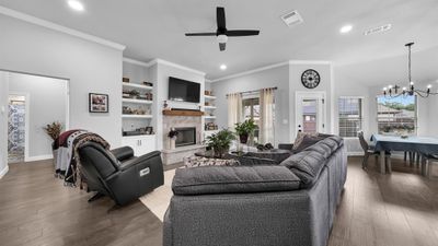 Living room with a fireplace, built in shelves, dark hardwood / wood-style flooring, and ceiling fan with notable chandelier | Image 2