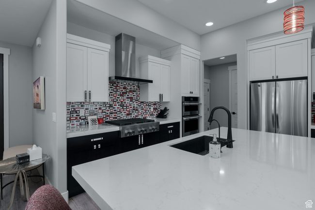 Kitchen featuring appliances with stainless steel finishes, wall chimney exhaust hood, a sink, recessed lighting, and light countertops | Image 24