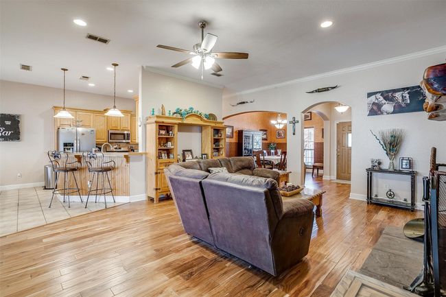 Living room with a ceiling fan, visible vents, arched walkways, and crown molding | Image 4