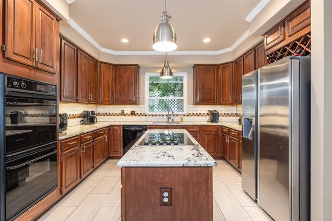 Kitchen featuring black appliances, a center island, tasteful backsplash, ceiling fan, and pendant lighting | Image 20