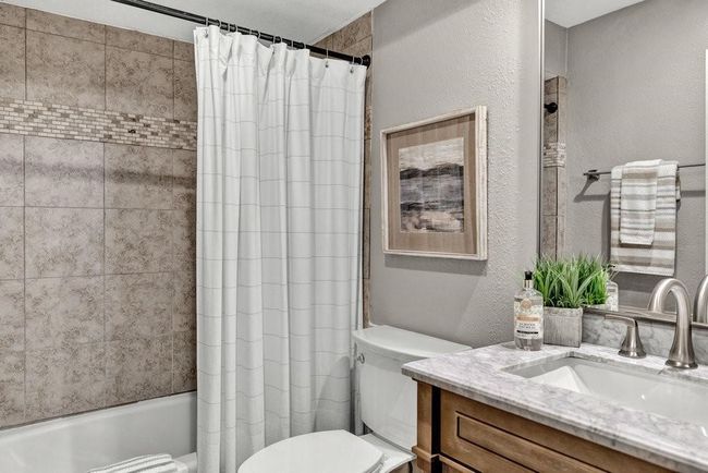 Full bath with a textured wall, shower / tub combo with curtain, toilet, and vanity | Image 19