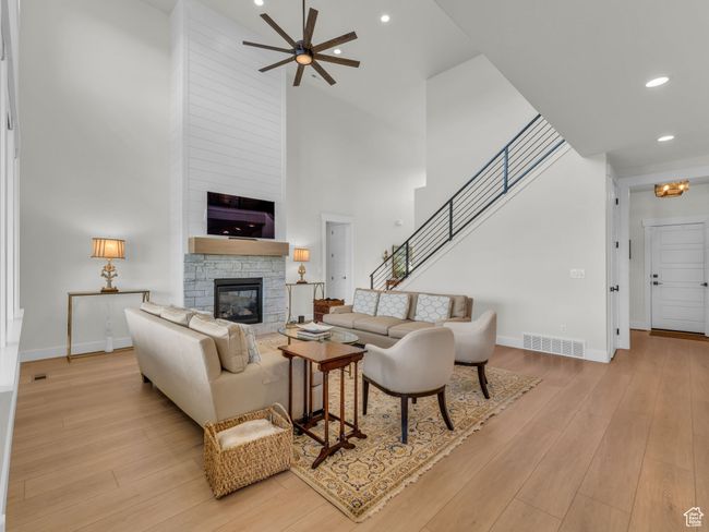 Living area featuring a high ceiling, a stone fireplace, a ceiling fan, baseboards, and recessed lighting | Image 8