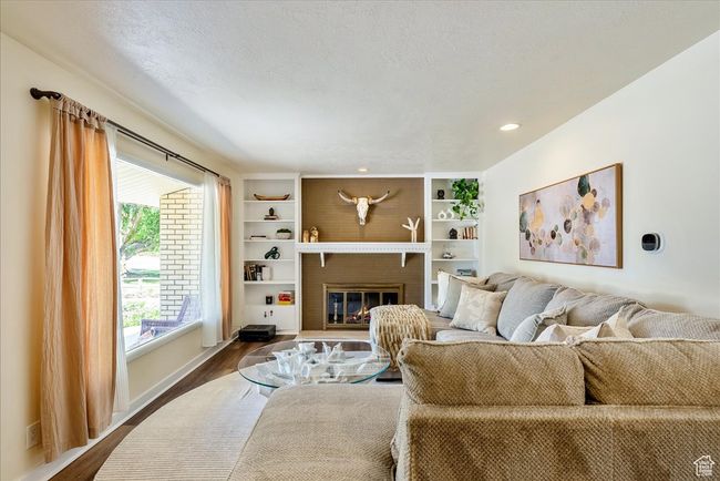 Living room featuring dark wood-style floors, a brick fireplace, a textured ceiling, and recessed lighting | Image 13