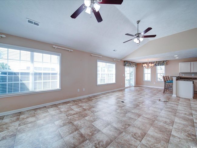 Unfurnished living room with ceiling fan, lofted ceiling, and a chandelier | Image 13