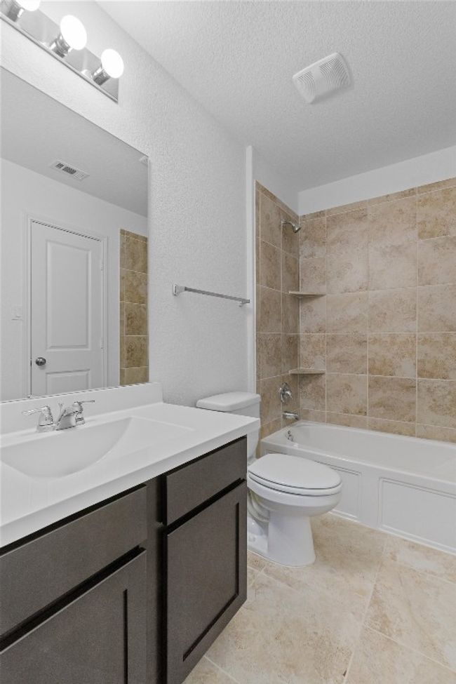 Bathroom with a textured ceiling, shower / tub combination, toilet, vanity, and visible vents | Image 27