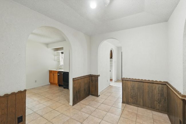 Unfurnished room featuring arched walkways, a textured ceiling, a sink, and light tile patterned floors | Image 11