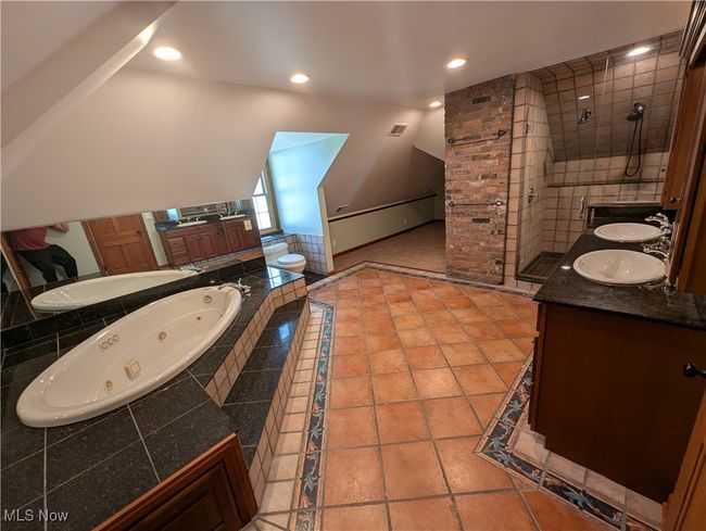 Bathroom featuring double vanity, a jetted tub, visible vents, a tile shower, and a sink | Image 4