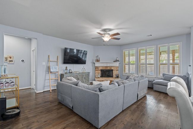 Living area with ceiling fan, dark wood-type flooring, a fireplace, and baseboards | Image 10