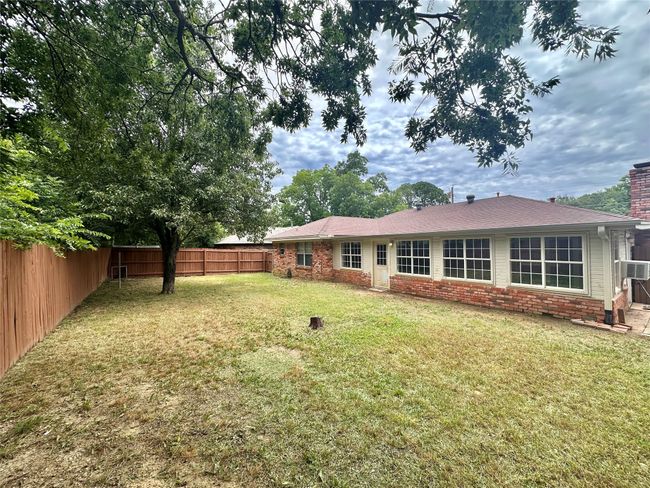 Rear view of property featuring a fenced backyard, brick siding, and a chimney | Image 35