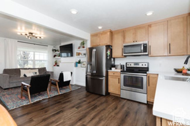 Kitchen with stainless steel appliances, light brown cabinets, a sink, light countertops, and dark wood finished floors | Image 16