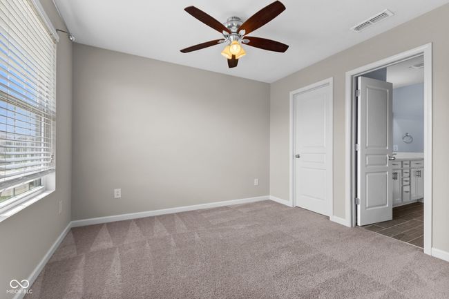 Bedroom with carpet flooring, connected bathroom, and ceiling fan | Image 21