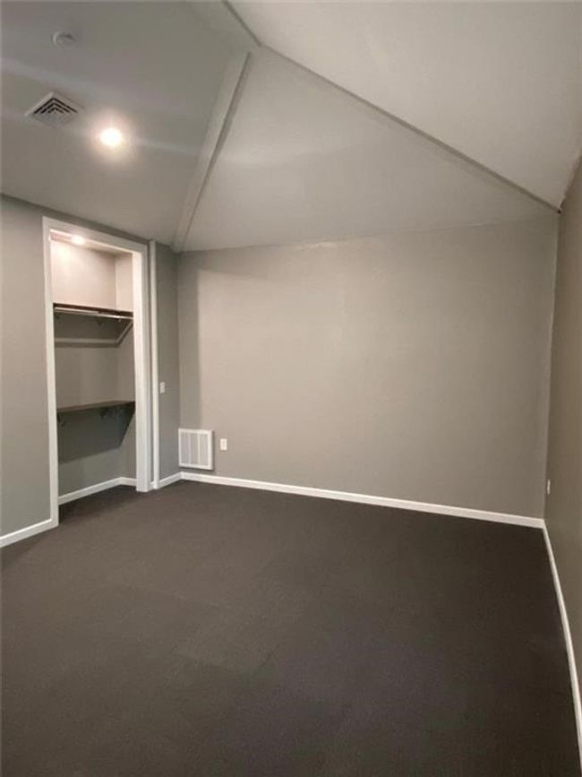 Unfurnished bedroom featuring a closet, lofted ceiling, a spacious closet, and dark carpet | Image 20