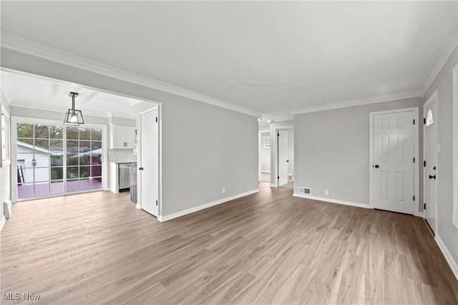 Unfurnished living room featuring visible vents, crown molding, light wood finished floors, and baseboards | Image 7