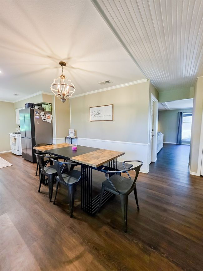 Dining area with dark wood-style flooring, baseboards, crown molding, and a chandelier | Image 21