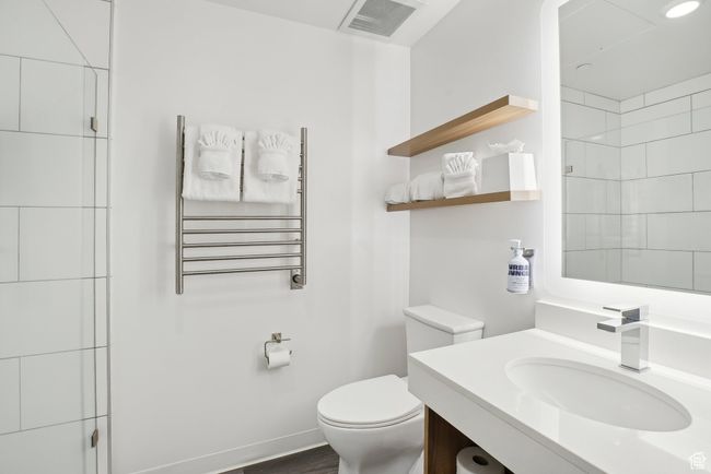 Bathroom featuring vanity, toilet, visible vents, radiator heating unit, and a shower | Image 20