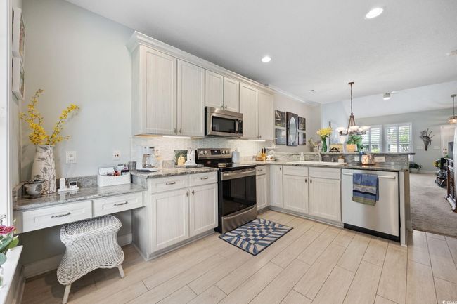Kitchen featuring a peninsula, stainless steel appliances, decorative backsplash, hanging light fixtures, and recessed lighting | Image 14