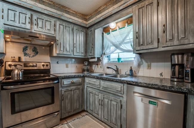 Kitchen with a sink, dark countertops, appliances with stainless steel finishes, and range hood | Image 10