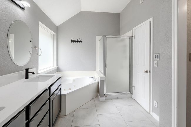 Bathroom featuring a shower stall, vanity, a whirlpool tub, and lofted ceiling | Image 24