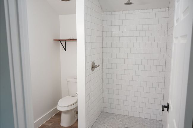 Bathroom featuring a shower stall and wood finished floors | Image 15