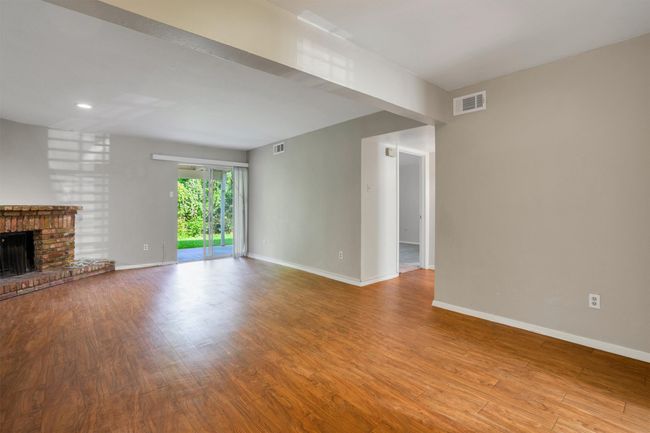 Unfurnished living room with finished floors, a brick fireplace, and recessed lighting | Image 9