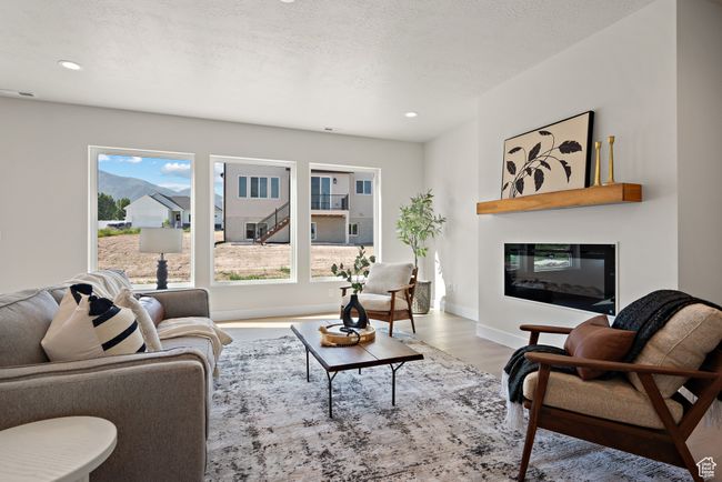 Living room featuring a glass covered fireplace, wood finished floors, plenty of natural light, and recessed lighting | Image 8