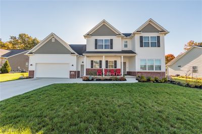 Craftsman house featuring a front lawn, covered porch, and a garage | Image 1