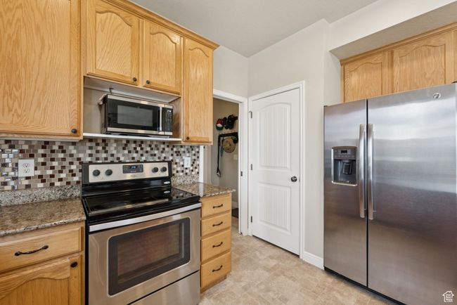 Kitchen with stainless steel appliances, tasteful backsplash, stone countertops, and light brown cabinetry | Image 15