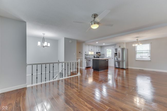 with ceiling fan with notable chandelier, dark wood finished floors, and baseboards | Image 5