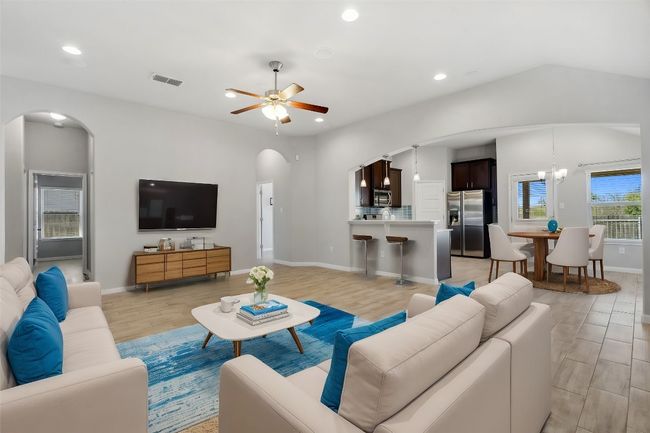 Virtually staged living area featuring arched walkways, recessed dimmable lighting, ceiling fan, and a lofted ceiling | Image 4