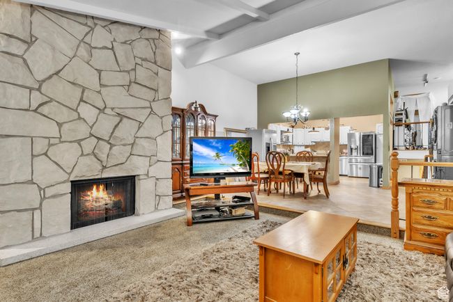 Living area with a chandelier, beam ceiling, and a stone fireplace | Image 9