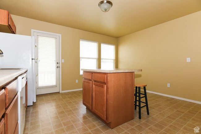 Kitchen featuring brown cabinets, a breakfast bar area, light countertops, and a wealth of natural light | Image 15
