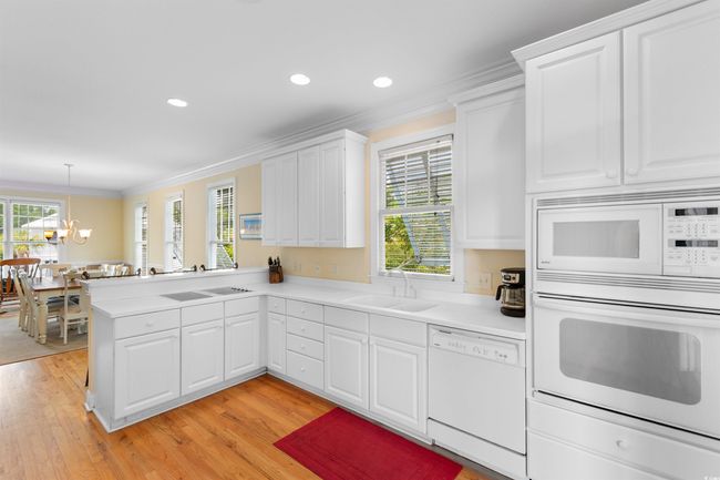 Kitchen with white appliances, a sink, crown molding, a chandelier, and light countertops | Image 6