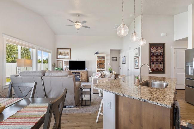 Kitchen featuring high vaulted ceiling, ceiling fan, open floor plan, light wood finished floors, and light stone counters | Image 10