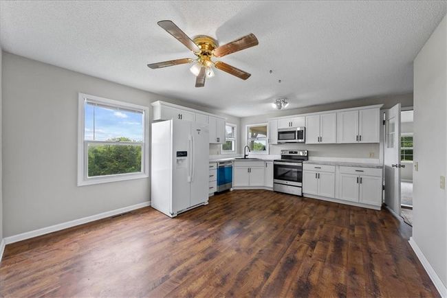 Kitchen with dark wood-style flooring, white cabinets, plenty of natural light, appliances with stainless steel finishes, and a sink | Image 58