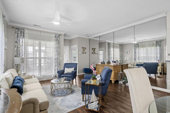 Living area with wood finished floors, ceiling fan, crown molding, and baseboards | Image 9