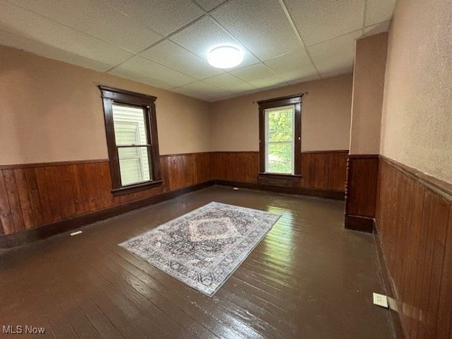 Empty room with a paneled ceiling, wood walls, and dark hardwood / wood-style flooring | Image 7