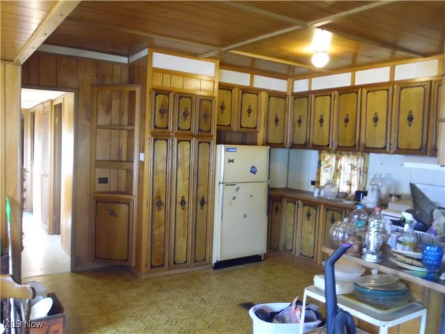 Kitchen featuring wood ceiling, white fridge, and wooden walls | Image 6