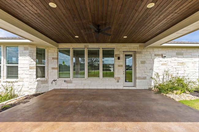 Doorway to property with ceiling fan, a patio, and stone siding | Image 28