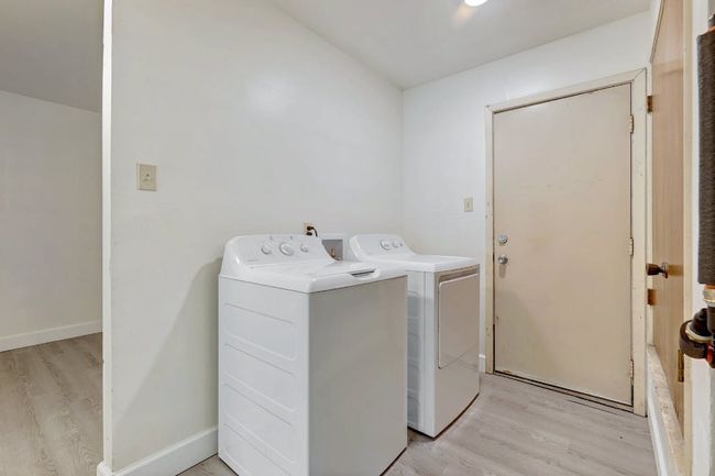 Laundry area with light wood-style flooring, washer and dryer, and baseboards | Image 24