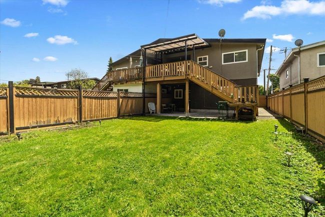 Back of house featuring stairway, a wooden deck, a lawn, a fenced backyard, and a patio area | Image 37